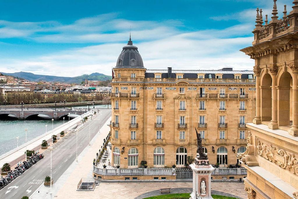 Ornate Belle Époque facade of Hotel Maria Cristina in San Sebastian, with grand arched windows and elegant French balconies at dusk