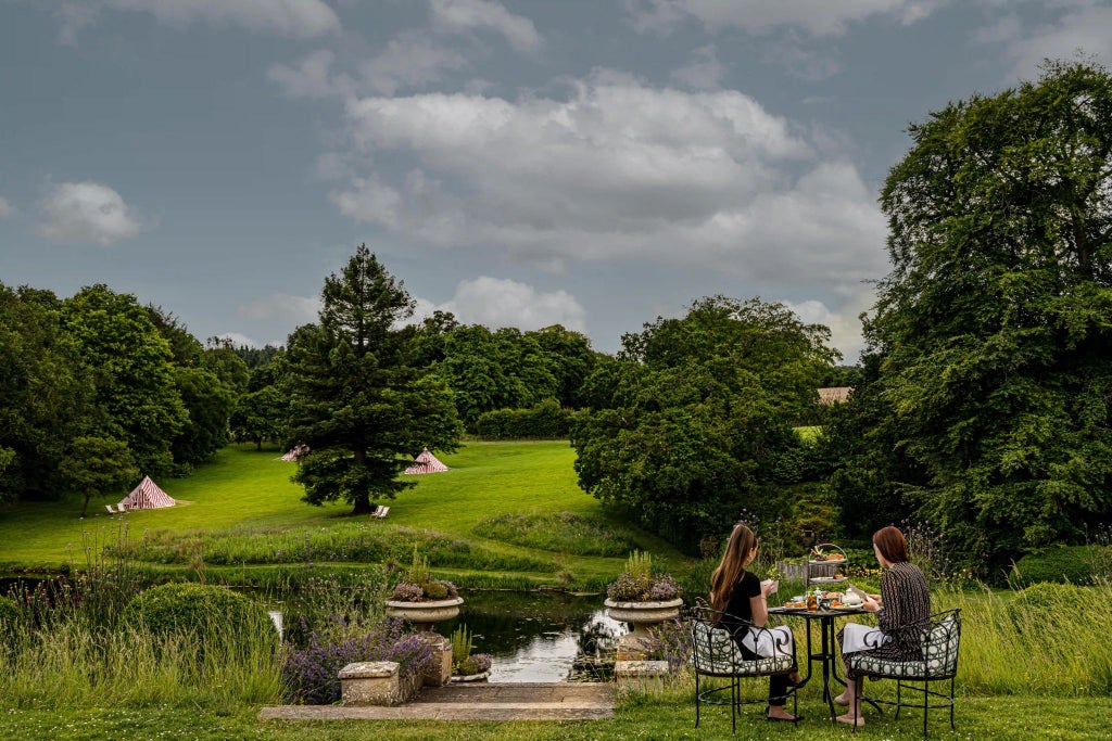 Luxurious countryside hotel with modern architecture, stone facade, manicured gardens, and expansive green lawns in scenic United Kingdom landscape