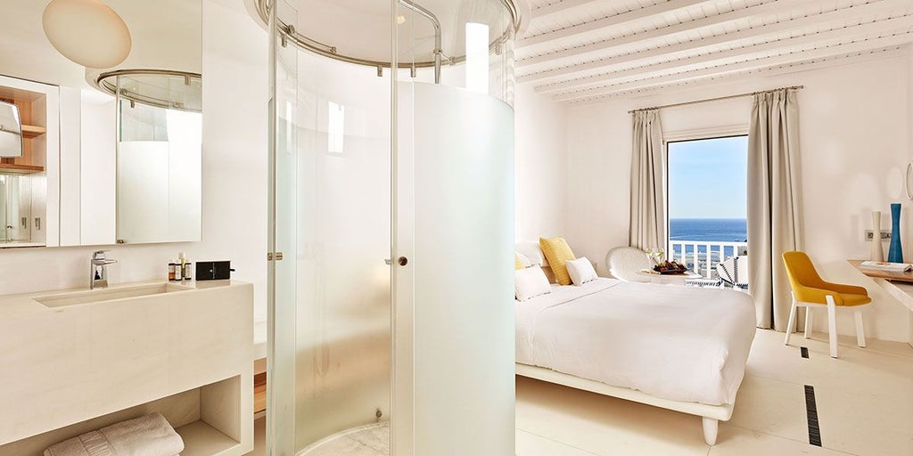 Luxurious blue-toned hotel room at Myconian Ambassador Hotel with minimal decor, panoramic sea view, and contemporary Greek island design aesthetic