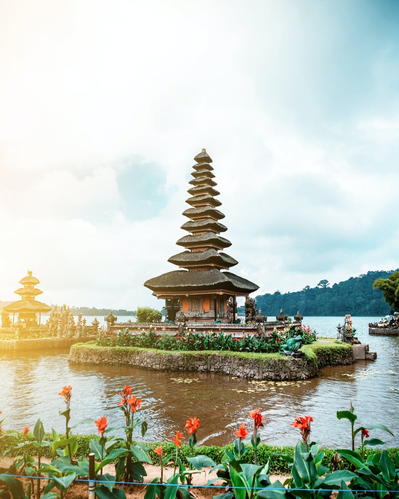 Golden sunlight bathes a luxurious Balinese infinity pool overlooking lush jungle, with romantic daybed and floating petals at sunset