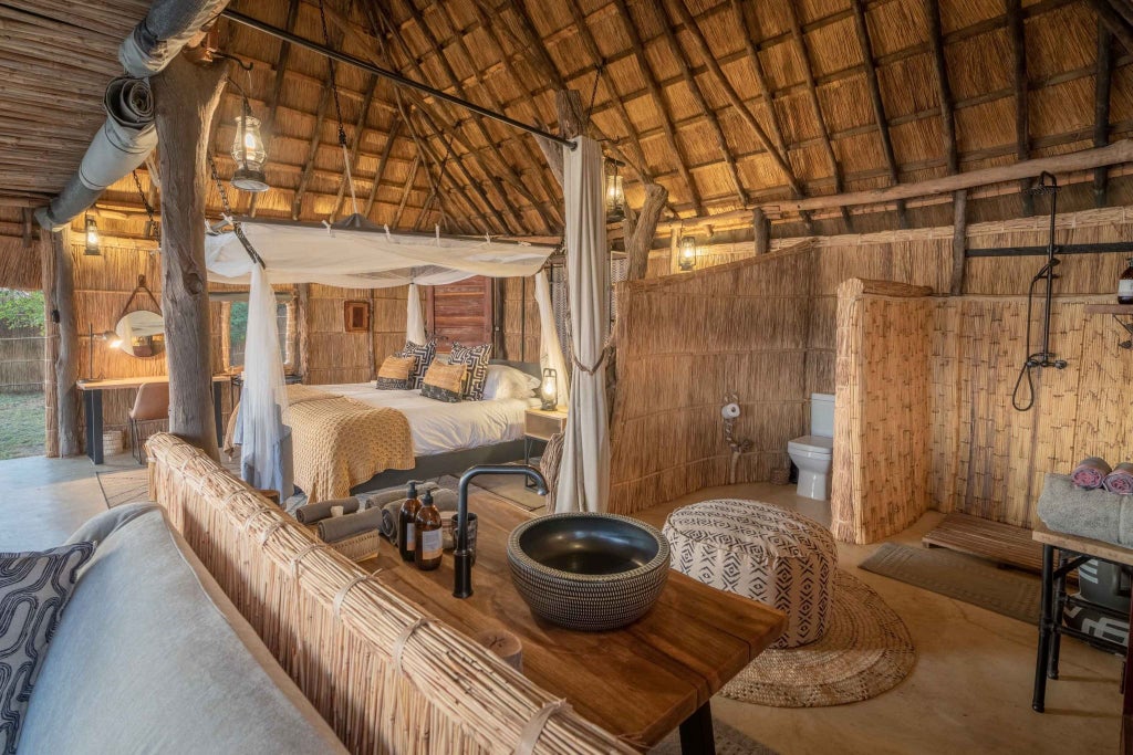 Luxurious safari tent overlooking Lower Zambezi River, with wooden deck, canvas walls, and lush wilderness landscape at sunset in Zambian national park.