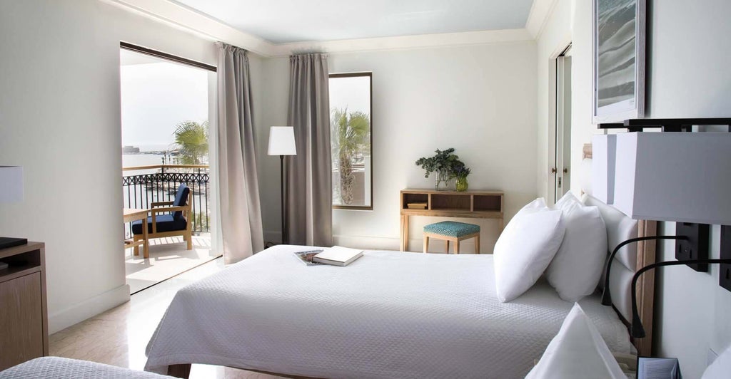 Luxurious sea view hotel room at scenset resort, featuring modern decor, plush white bedding, and panoramic Cyprus coastline through floor-to-ceiling windows