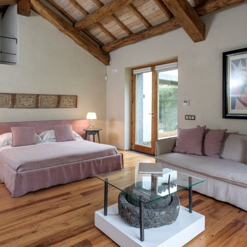 Elegant junior suite with panoramic Etna views, featuring rustic-chic design, natural wood furnishings, and soft neutral palette in a boutique Sicilian countryside setting