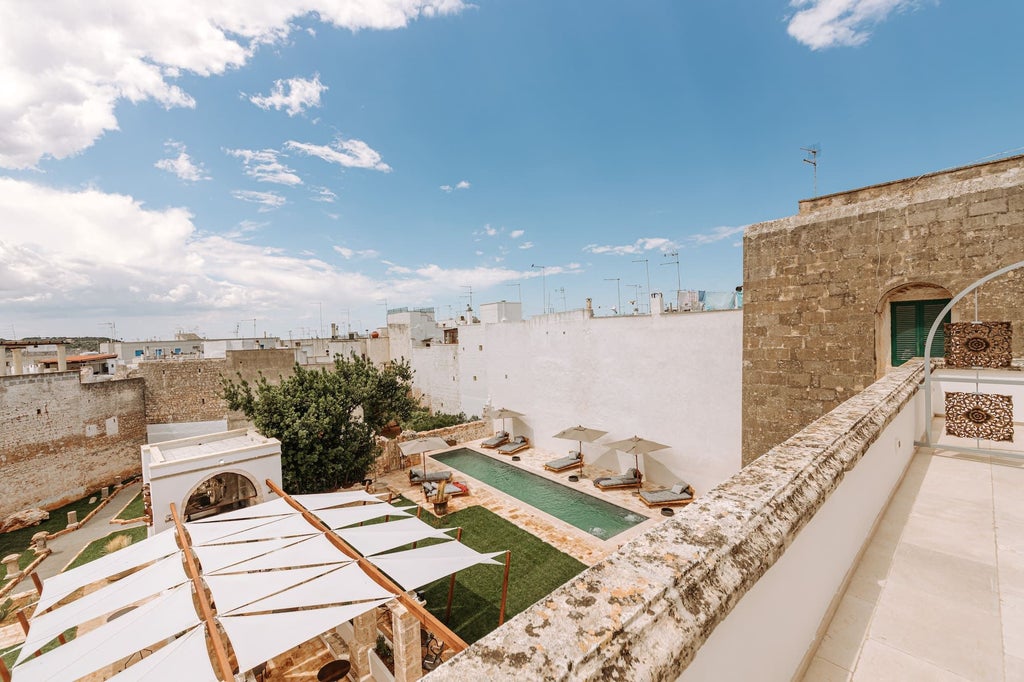 Opulent Italian boutique hotel suite with elegant marble bathroom, plush king bed, and panoramic window overlooking historic architecture in Puglia