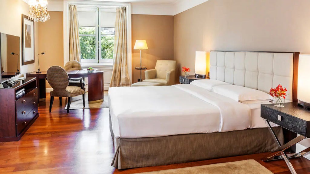 Elegant white king bedroom with crystal chandelier, French windows, marble bathroom and city views in palatial Buenos Aires suite