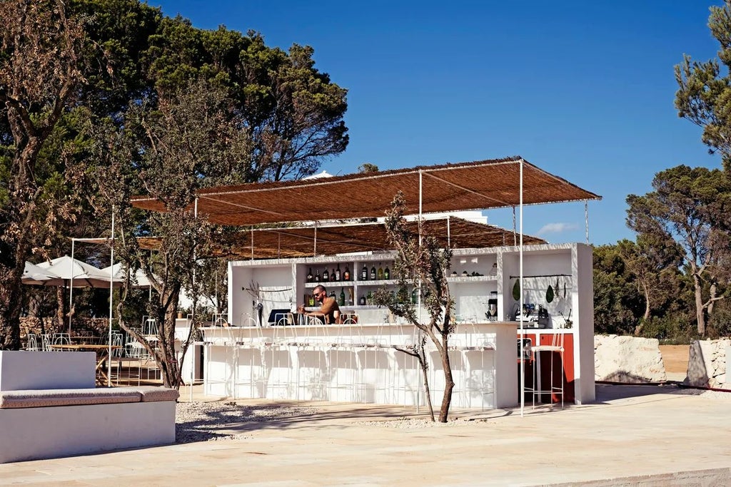 Luxurious whitewashed Menorca Experimental hotel exterior with Mediterranean stone walls, lush greenery, and rustic chic design overlooking Balearic coastline