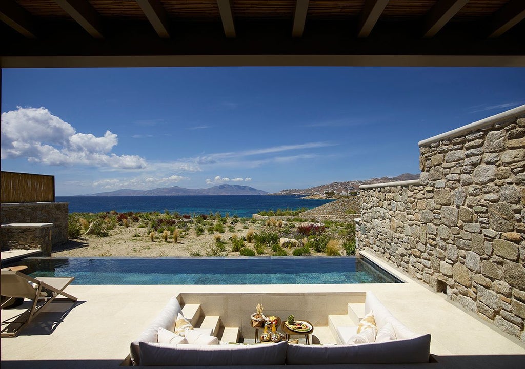 Luxurious one-bedroom villa in Mykonos with private heated pool, stunning sea view, and elegant white architecture against the azure Aegean backdrop.