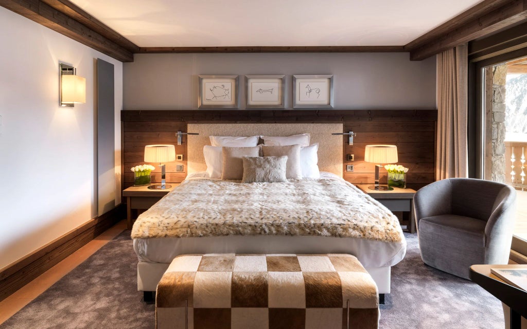 Spacious alpine luxury suite with panoramic mountain views, contemporary design, wood accents, and elegant furnishings in Courchevel ski resort