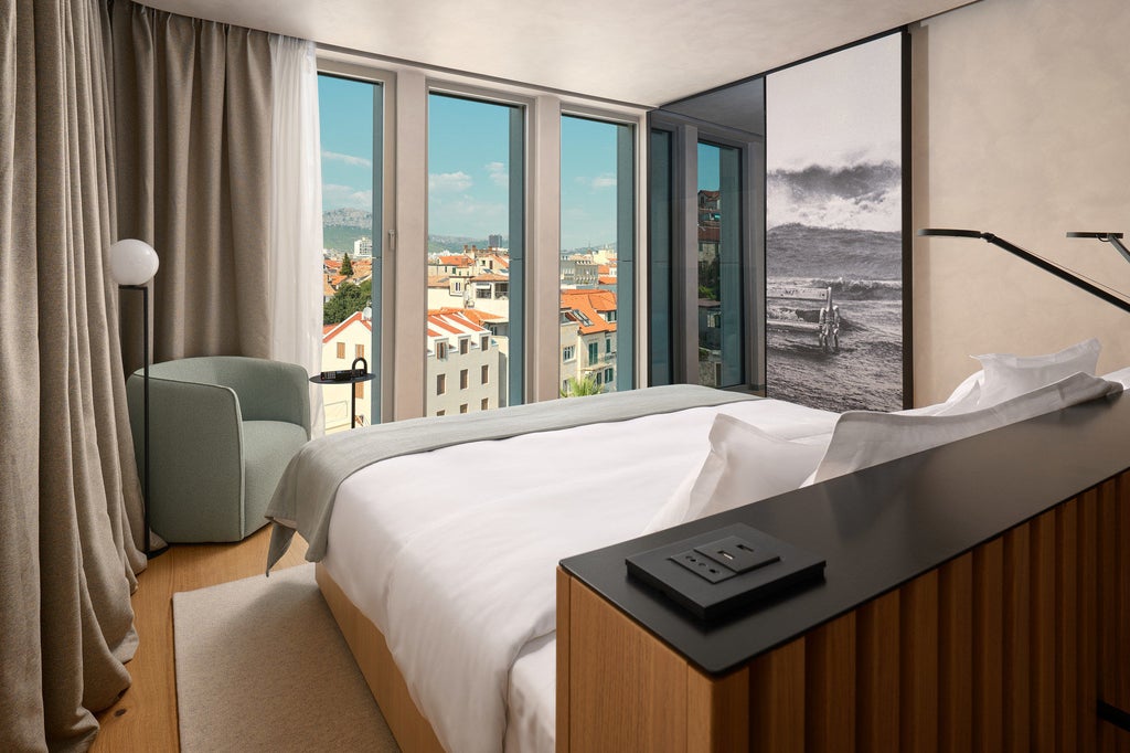 Elegant superior hotel room with twin beds, crisp white linens, rich wooden furniture and panoramic window overlooking Croatian scenery