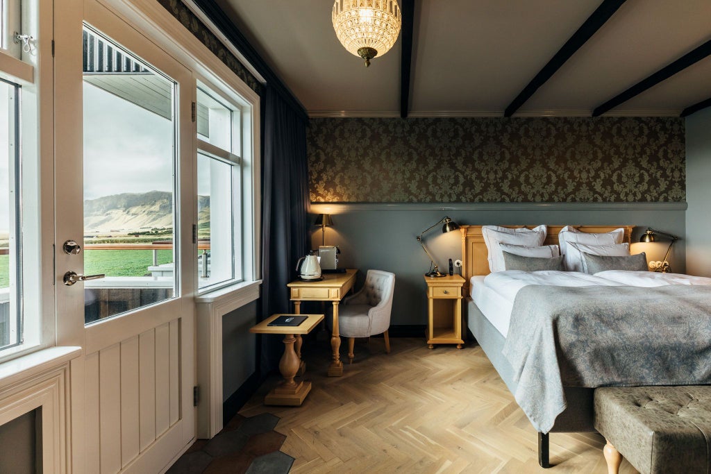 Luxurious Icelandic hotel room with elegant wooden furnishings, plush king-sized bed, large windows overlooking scenic landscape, warm neutral color palette