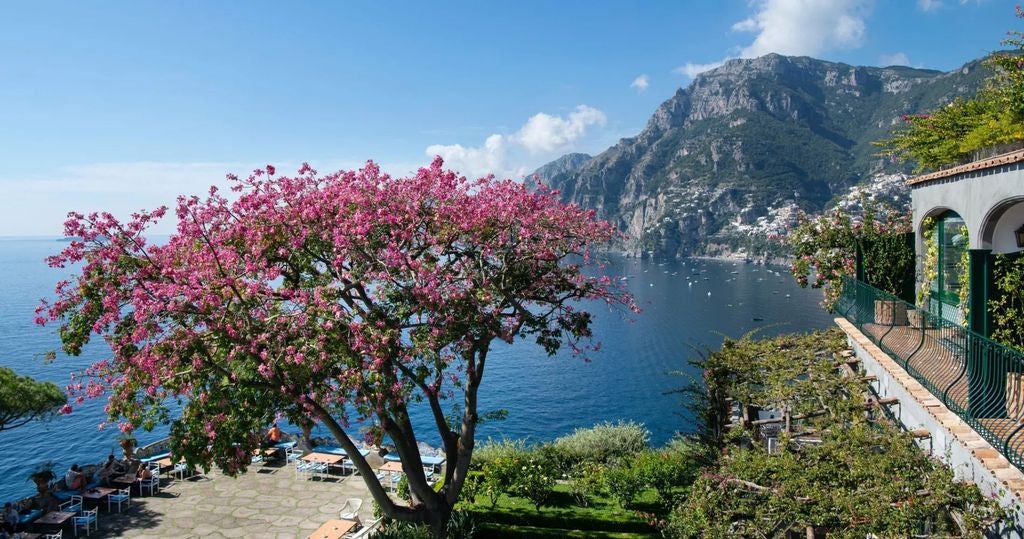 Elegant cliffside hotel in Positano with terraced balconies overlooking the Amalfi Coast, Mediterranean Sea and colorful village below