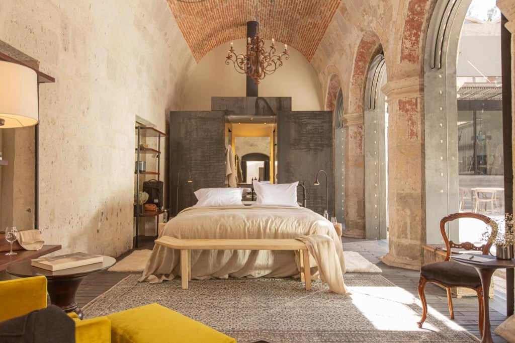 Historic Peruvian luxury hotel with white stone arches, rustic wooden beams, and artisanal furnishings in a colonial courtyard setting