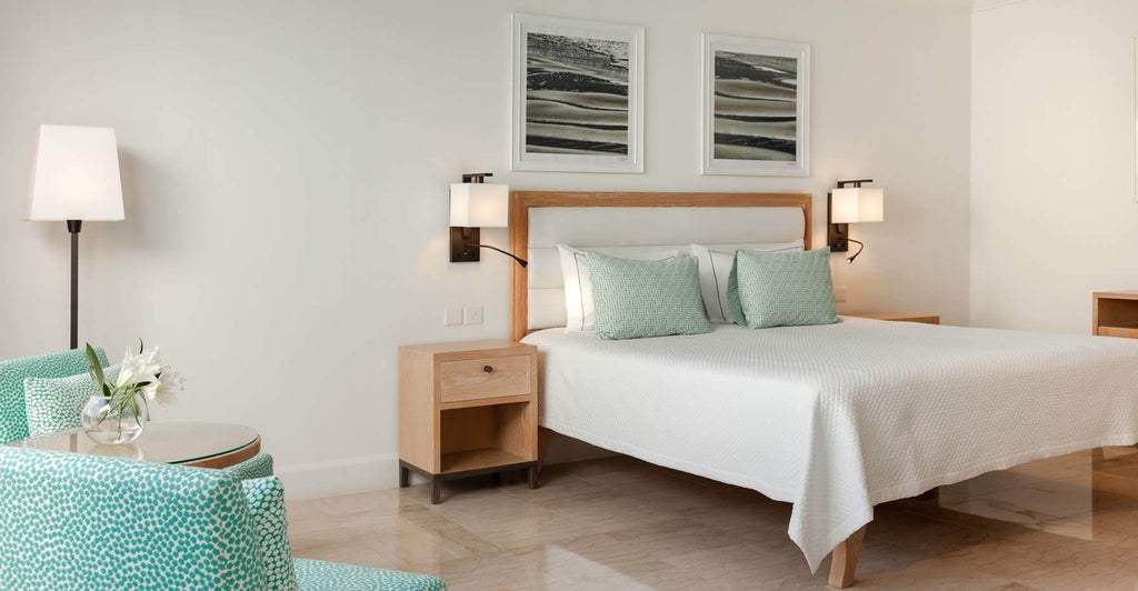 Spacious Superior Sea View Suite at coastal Cyprus hotel with elegant king bed, expansive blue Mediterranean vista, and modern minimalist luxury decor