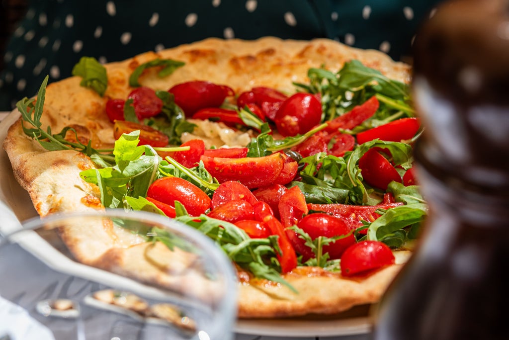 Locals gather at an elegant Roman osteria, sharing artisanal cheeses and wine under vintage ceiling frescoes in a warm-lit setting