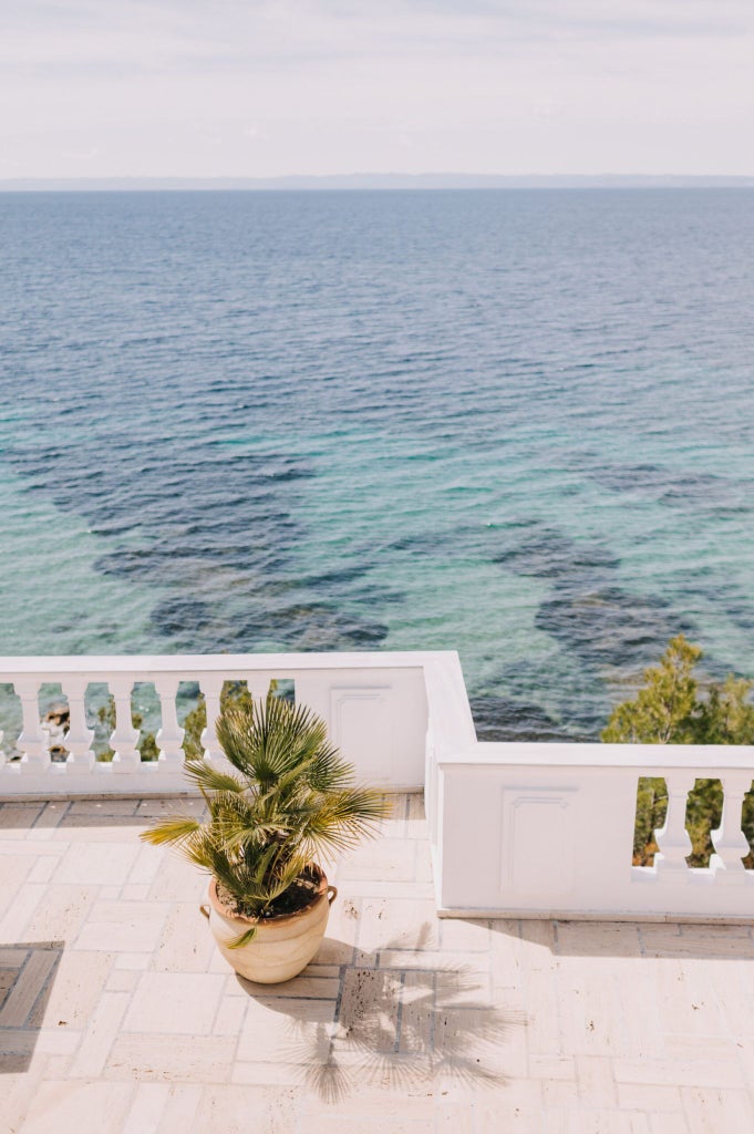 Luxurious white minimalist villa bedroom with panoramic Aegean Sea view, sleek modern design, and elegant coastal Greek island architecture