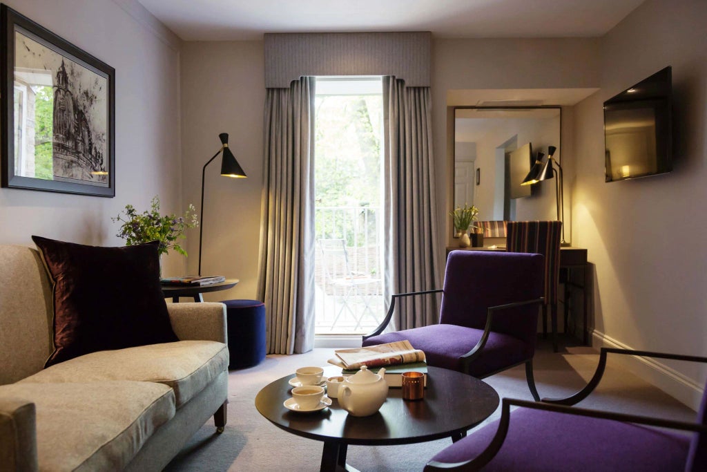 Elegant suite at Old Bank Hotel with plush king bed, ornate wooden furnishings, soft neutral color palette, and refined British architectural details