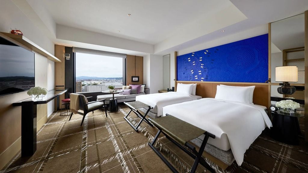 Modern twin hotel room with floor-to-ceiling windows, city views, plush beds, minimalist decor, and warm wood accents at Hyatt Centric Kanazawa