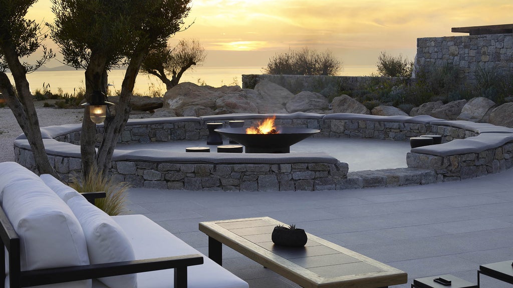 Luxurious whitewashed Greek villa with infinity pool overlooking Aegean Sea, modern pergolas and bougainvillea at sunset in Mykonos