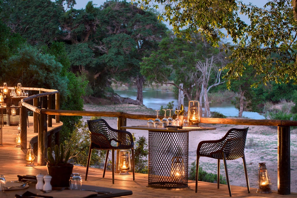 Luxurious safari lodge suite with private plunge pool overlooking African bush, featuring floor-to-ceiling glass walls and wooden deck.