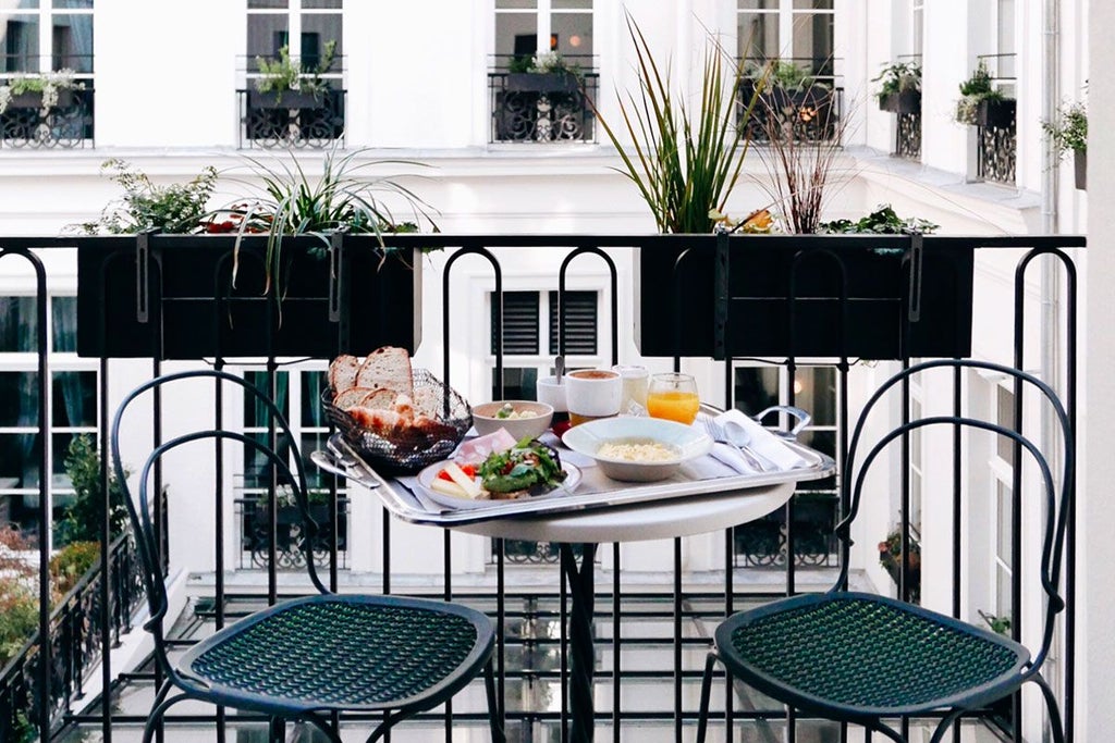 Elegant Parisian hotel room with ornate French balcony overlooking classic boulevards, featuring plush white linens and sophisticated vintage decor