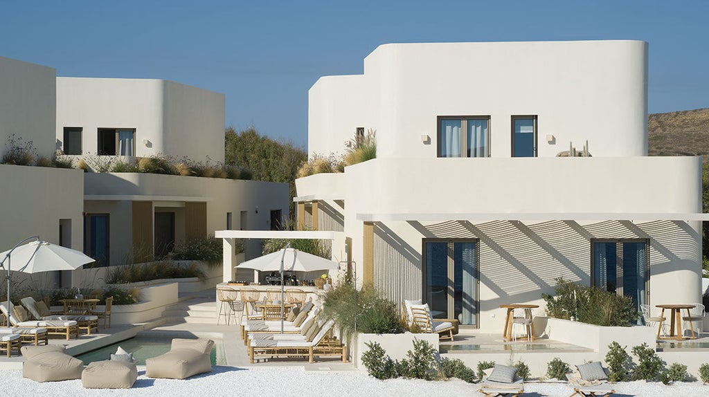 White luxury suite with curved architecture and private infinity pool overlooking the Aegean Sea and Santorini caldera at sunset