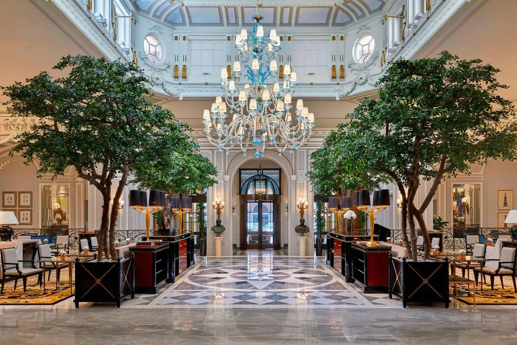 Ornate marble facade of St. Regis Rome hotel with Renaissance-style architecture, elegant arched windows and wrought iron balconies.