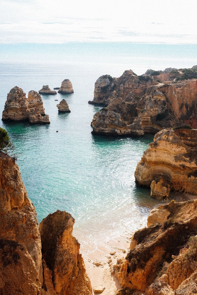 Aerial view of luxury Algarve coast featuring rugged golden cliffs, turquoise waters, pristine beaches and upscale resort villas