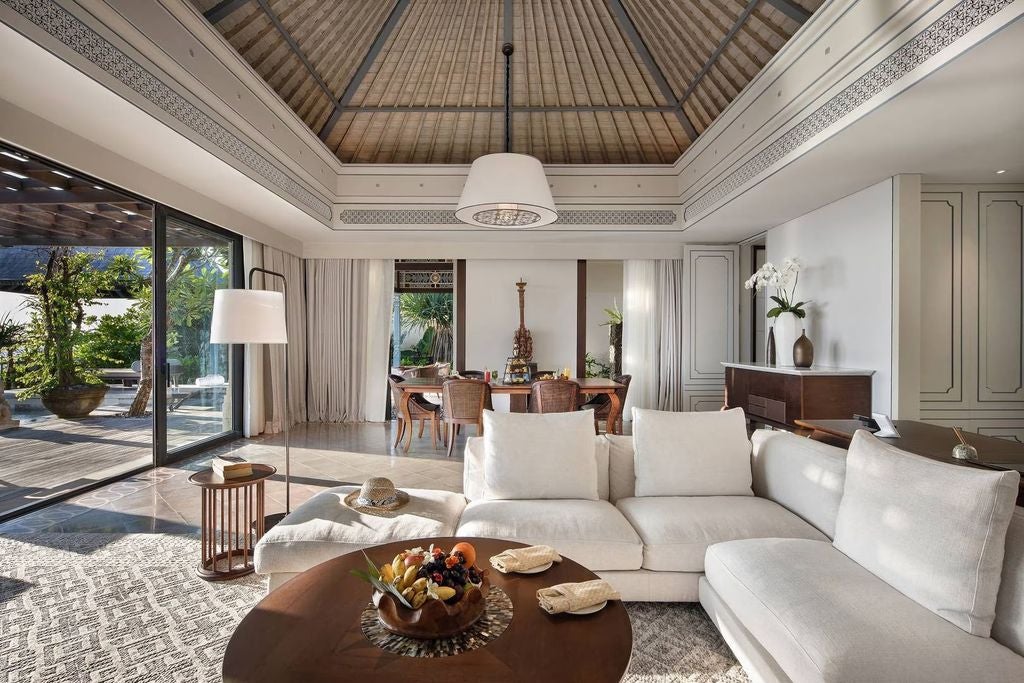 Luxurious two-story villa with infinity pool surrounded by lush tropical gardens, featuring Balinese architecture and private terrace seating