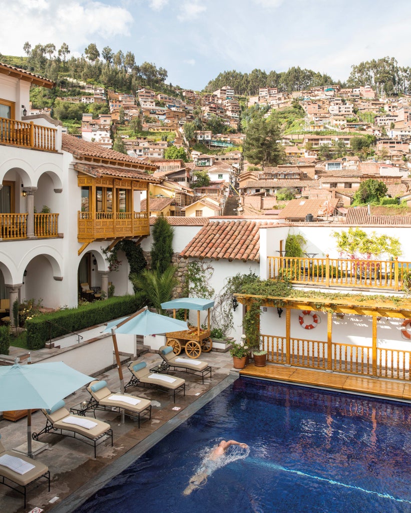 Historic luxury hotel in Cusco with stone archways, ornate colonial architecture, and manicured courtyard featuring a central fountain