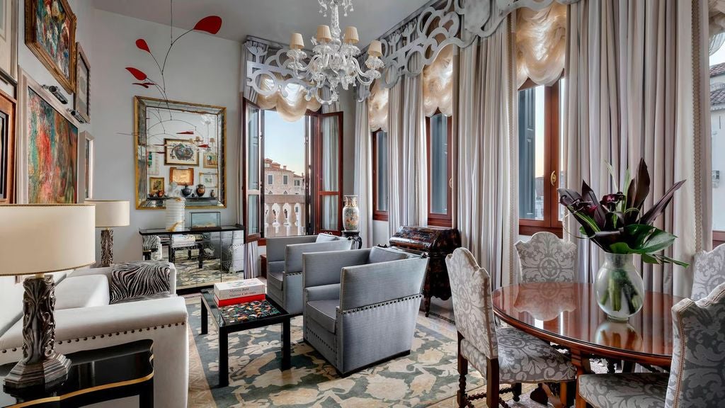 Opulent Venetian suite with crystal chandeliers, antique furnishings, damask wallpaper, and floor-to-ceiling windows overlooking Canal views