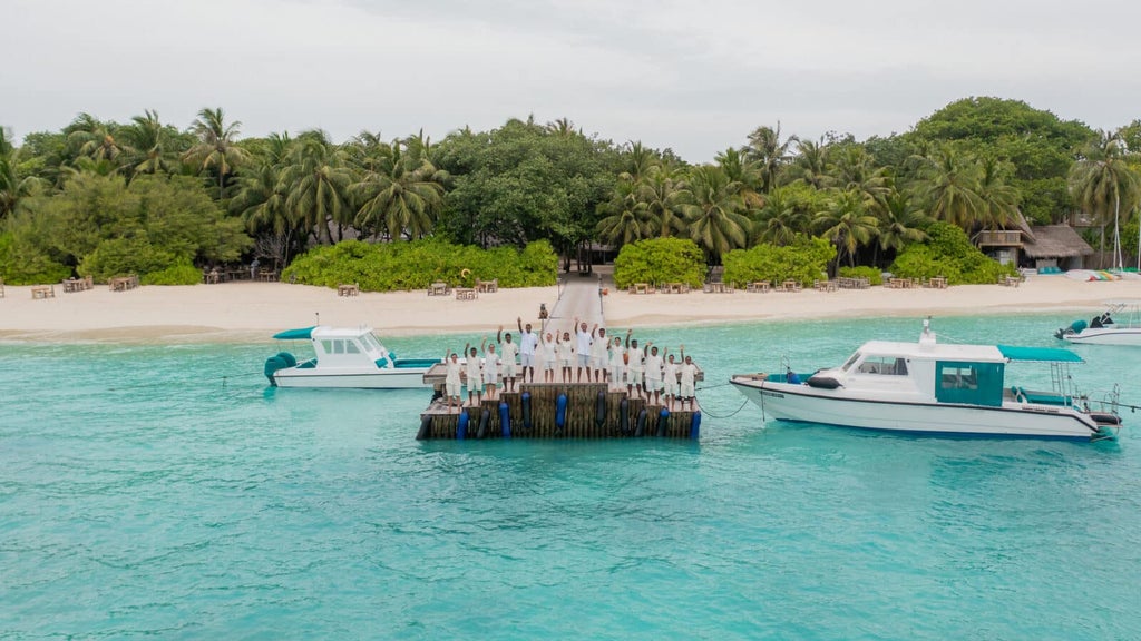 Overwater luxury villa with private infinity pool suspended above turquoise Maldivian lagoon, surrounded by palm trees at sunset