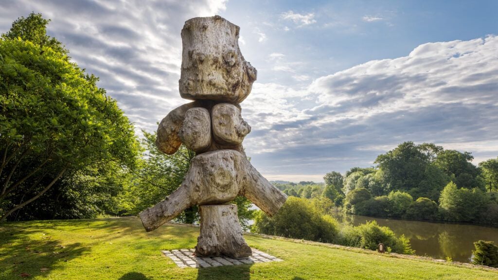 Luxurious French countryside chateau with stone walls, surrounded by lush green meadows and serene water reflections at golden hour