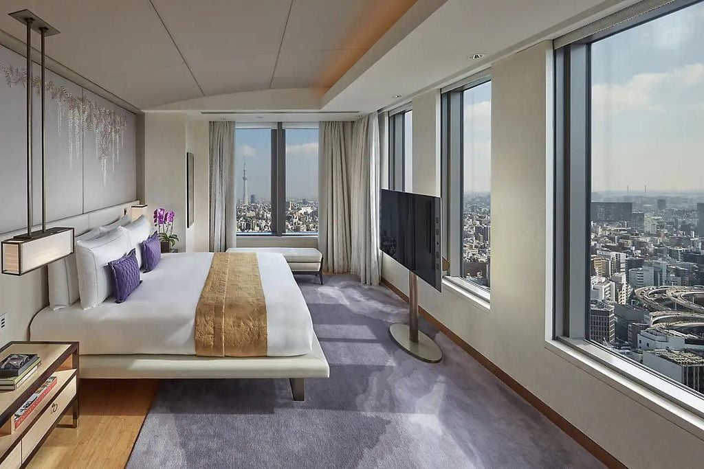 Luxurious corner suite with panoramic Tokyo views, featuring modern Asian decor, plush king bed, and elegant marble bathroom with soaking tub