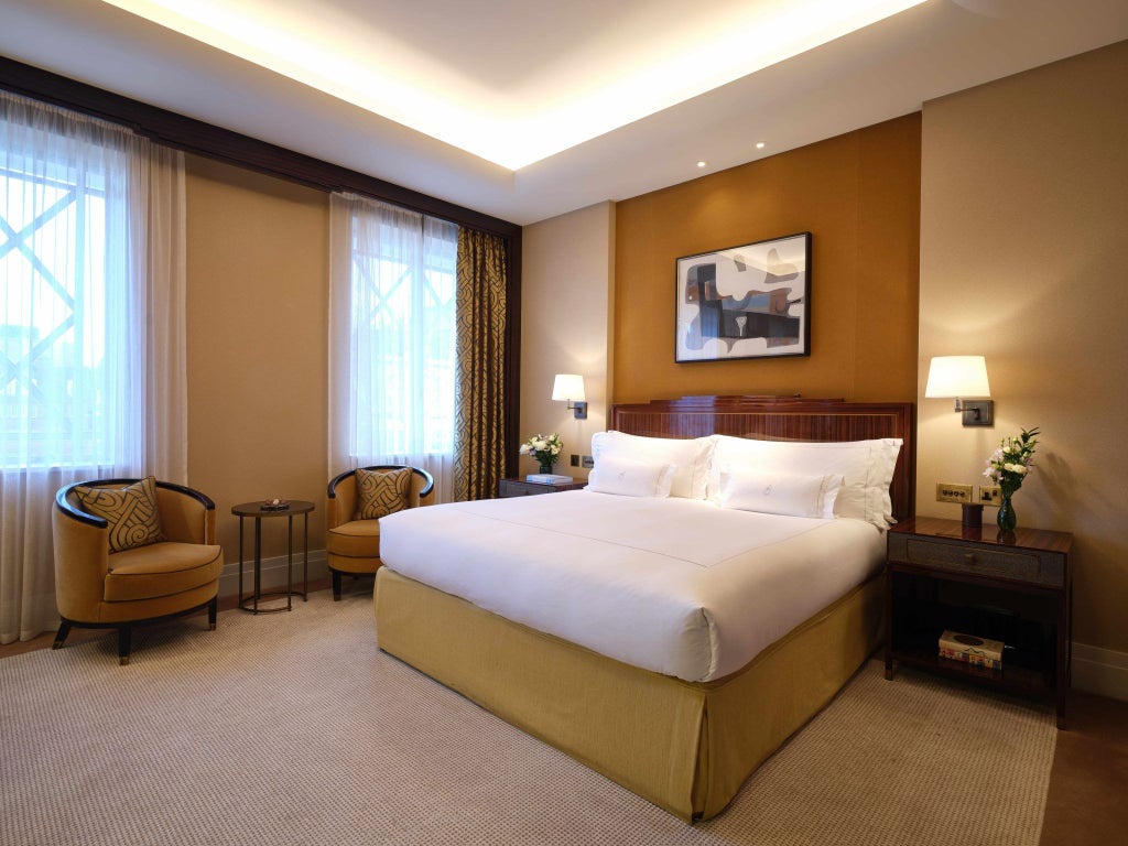 Elegant classic hotel room with plush cream-colored furnishings, rich wooden accents, soft lighting, and refined British hospitality design in Mayfair, London