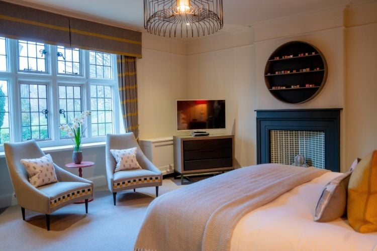 Elegant oak-paneled hotel room at Foxhill Manor, showcasing luxurious traditional British design with plush furnishings and warm, inviting woodland-inspired color palette