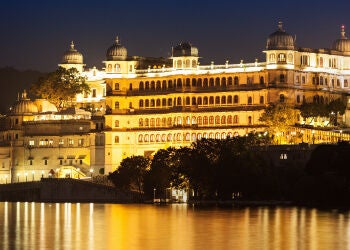 Elegant resort with grand domed architecture overlooking Lake Udai Sagar, featuring white marble facades and lush palace gardens