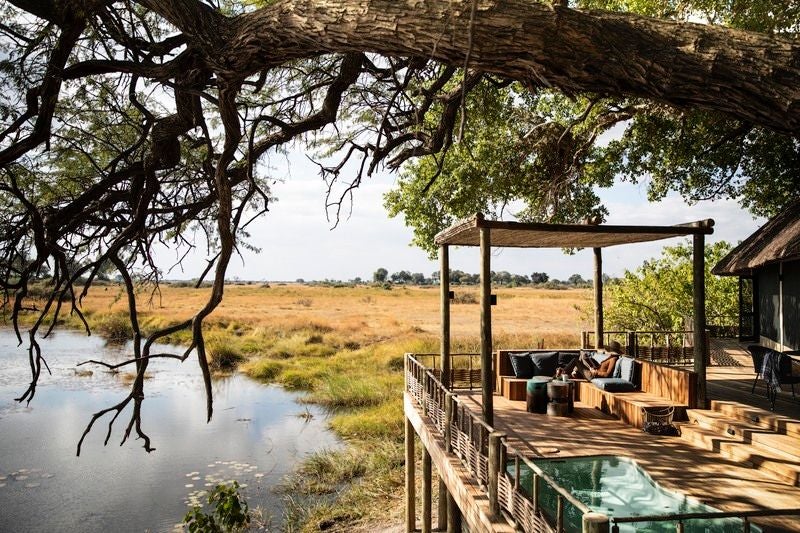 Elevated luxury safari suite with private plunge pool overlooking Linyanti River, surrounded by wild African savanna at sunset