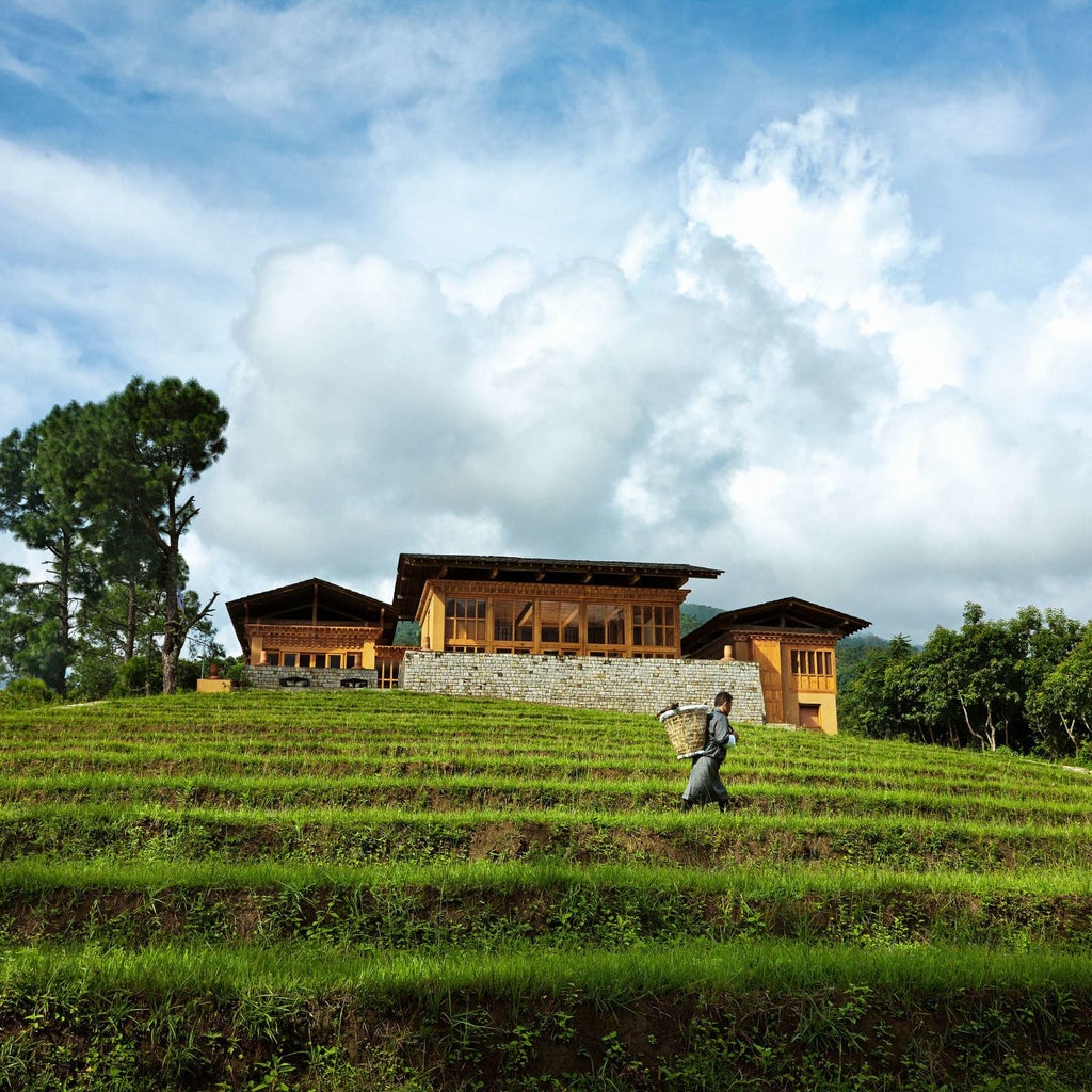 Luxurious riverside hotel nestled in Bhutan's lush Punakha Valley, with traditional Himalayan architecture, elegant white walls, and verdant mountain backdrop