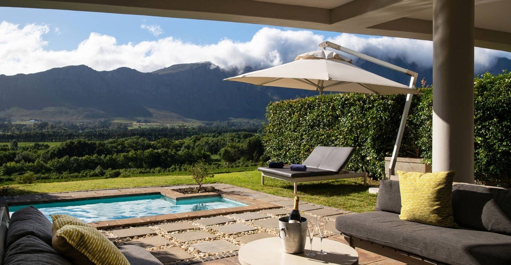 Luxurious CAP Classique Suite at Mont Rochelle, featuring elegant king bed, plush furnishings, and expansive vineyard views in South African wine country