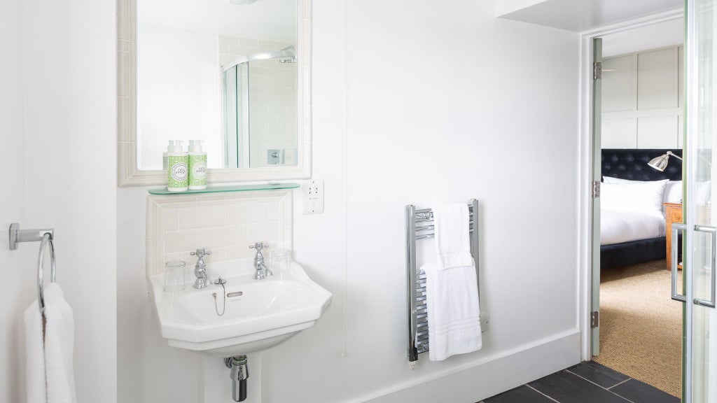 Modern, minimalist shower room with sleek glass enclosure, neutral stone tiles, and contemporary design in luxurious boutique accommodation located in United Kingdom.