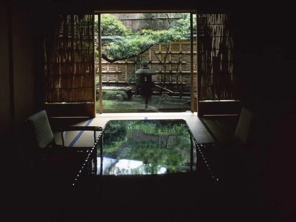 Traditional Japanese ryokan with elegant wooden facade, featuring sliding shoji screens, ornate roof tiles, and lanterns casting warm light