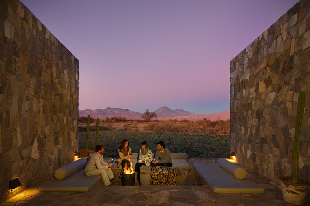 Sleek desert resort with infinity pool reflecting Atacama's volcanoes, modern wood-glass architecture under clear blue sky