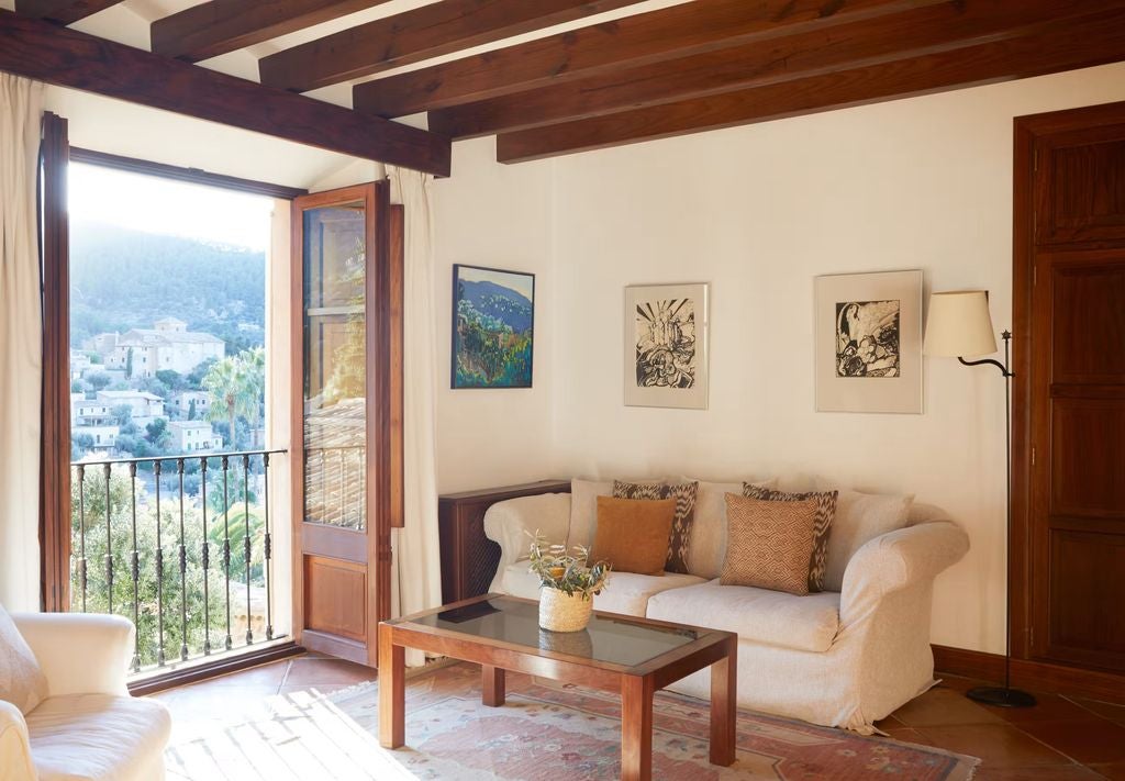 Elegant mountain-view suite with rustic stone walls, terracotta floors, plush king bed, antique furnishings and private balcony in Mallorca