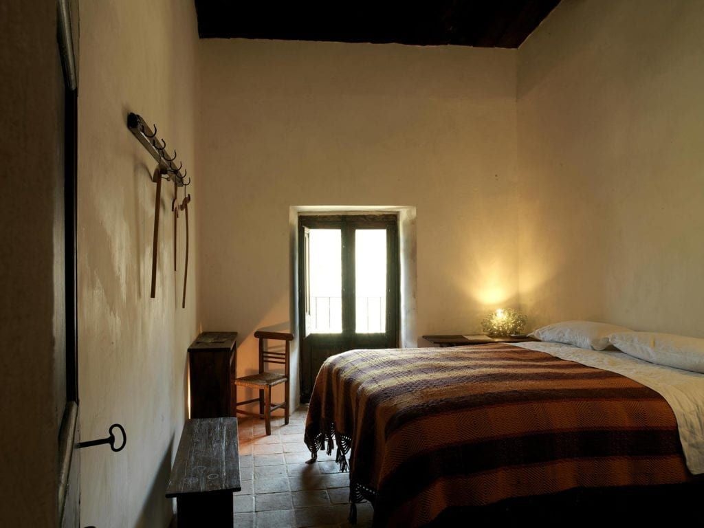 Rustic stone walls, elegant wooden furnishings, and soft natural light in a luxurious Superior room at Sextantio Albergo Diffuso, nestled in an Italian historic village.