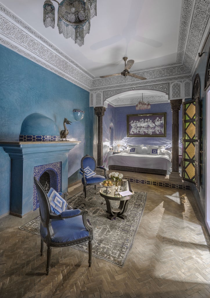 Opulent Moroccan riad hotel with ornate arches, traditional lanterns, and marble columns surrounding a tranquil courtyard fountain pool