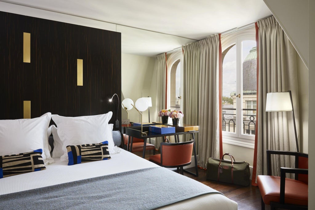 Elegant Parisian junior suite with soft neutral tones, plush king bed, contemporary designer furniture, and large windows overlooking urban landscape