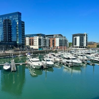 Luxurious waterfront hotel with modern glass facade, situated along Southampton's harbor, reflecting elegant maritime architecture and scenic coastal setting