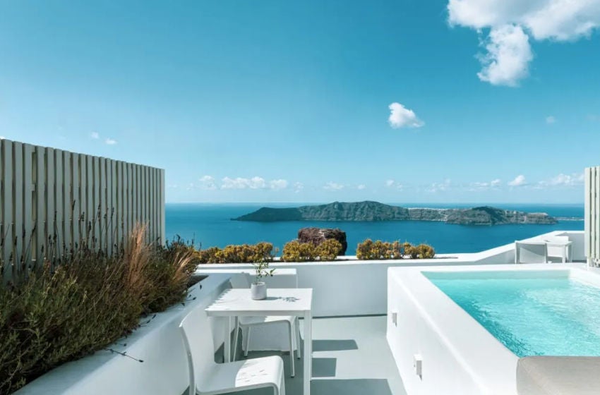 Luxurious white cave-style suite with private plunge pool overlooking Santorini caldera, featuring elegant minimalist Mediterranean decor