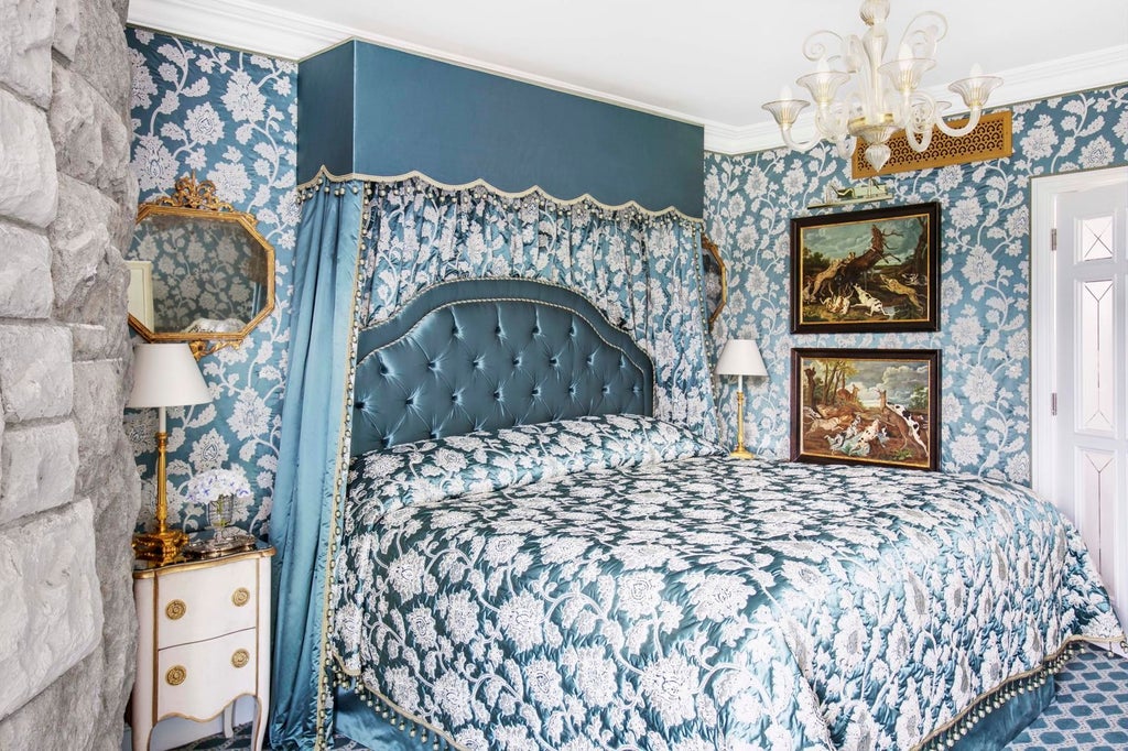 Elegant medieval-style hotel suite with ornate furnishings, crystal chandelier, canopy bed, and panoramic windows overlooking Irish castle grounds