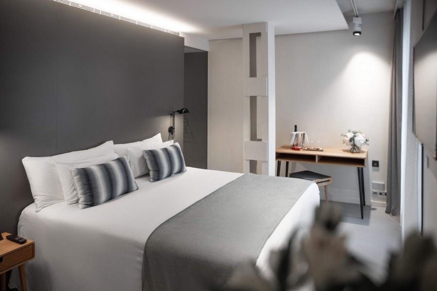 Modern minimalist hotel room with sleek white decor, clean lines, large window, and contemporary furnishings at upscale Barcelona accommodation